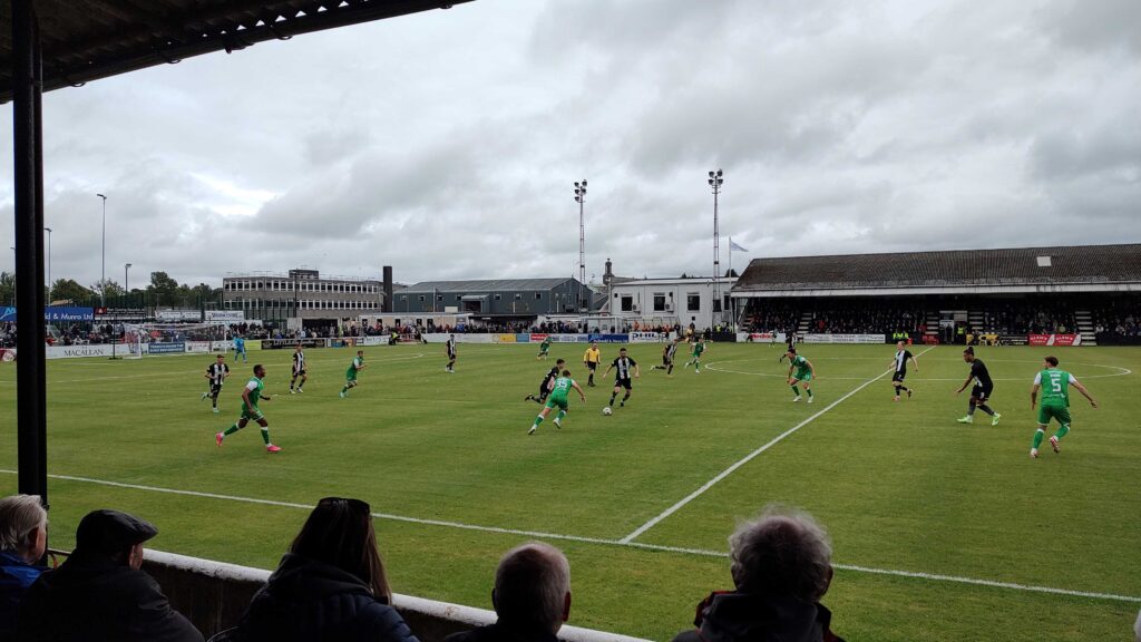 Elgin City and Hibs players contest the ball in midfield.
